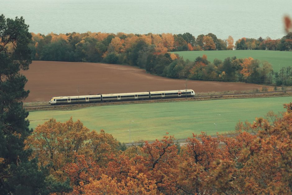 A serene scene of a train traveling through vibrant autumn landscapes in Jönköping, Sweden