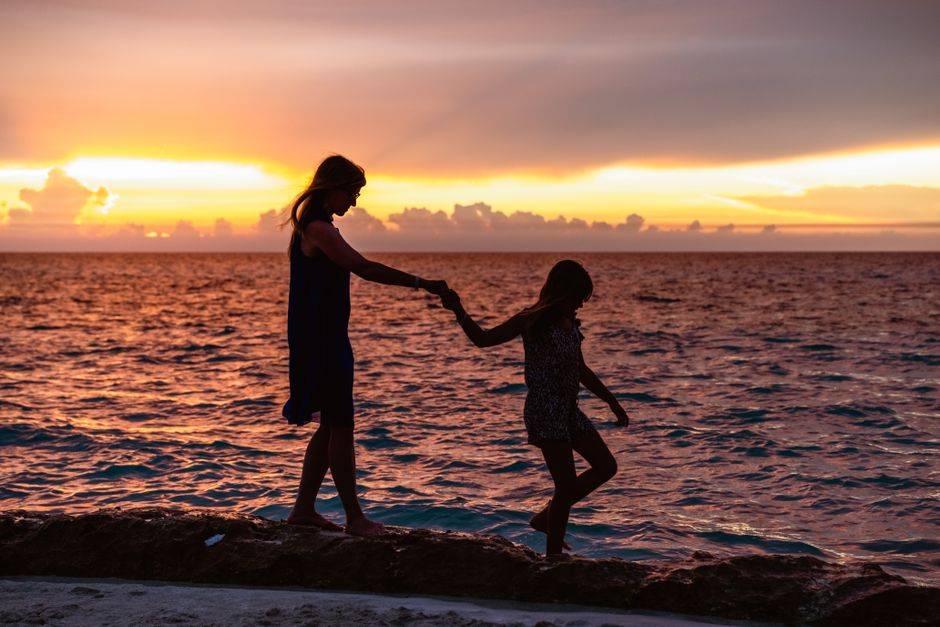 A mother and daughter hold hands walking along the beach at sunset in Varadero, Cuba.