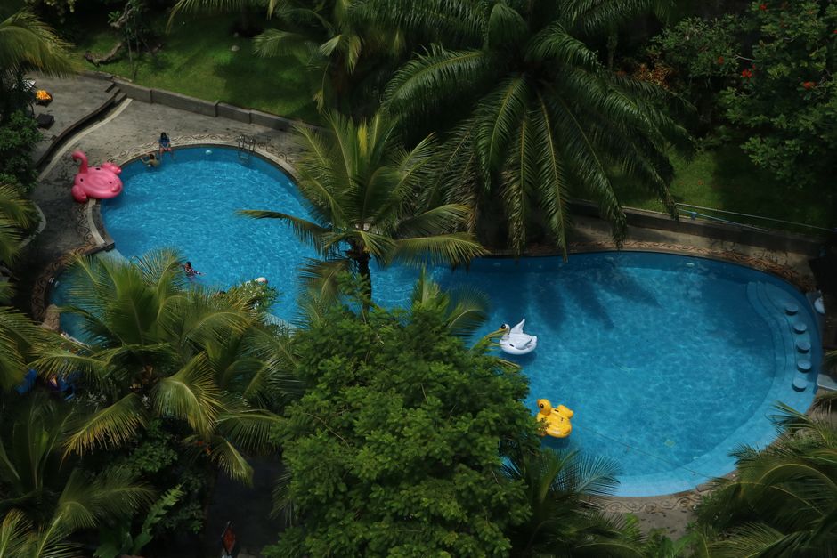 Aerial view of a tropical resort pool surrounded by lush greenery in Malang, Indonesia.