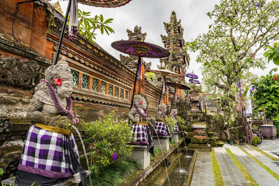 Explore the intricate details of a traditional Balinese temple adorned with guardian statues and vibrant decorations.