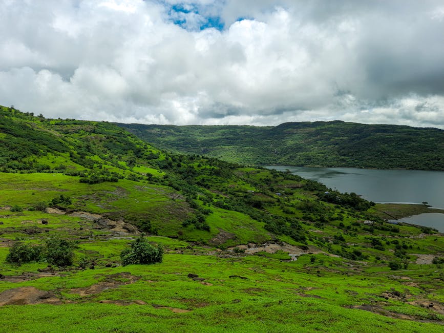Scenic view of green hills and lake under cloudy skies in Lonavla, MH, India.