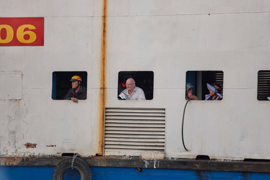 A diverse group of people looking out from ship windows in Ho Chi Minh City, Vietnam.