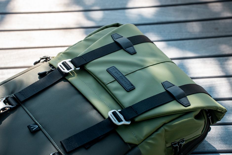 Close-up of a modern olive green backpack with black straps on a wooden surface, perfect for outdoor adventures.