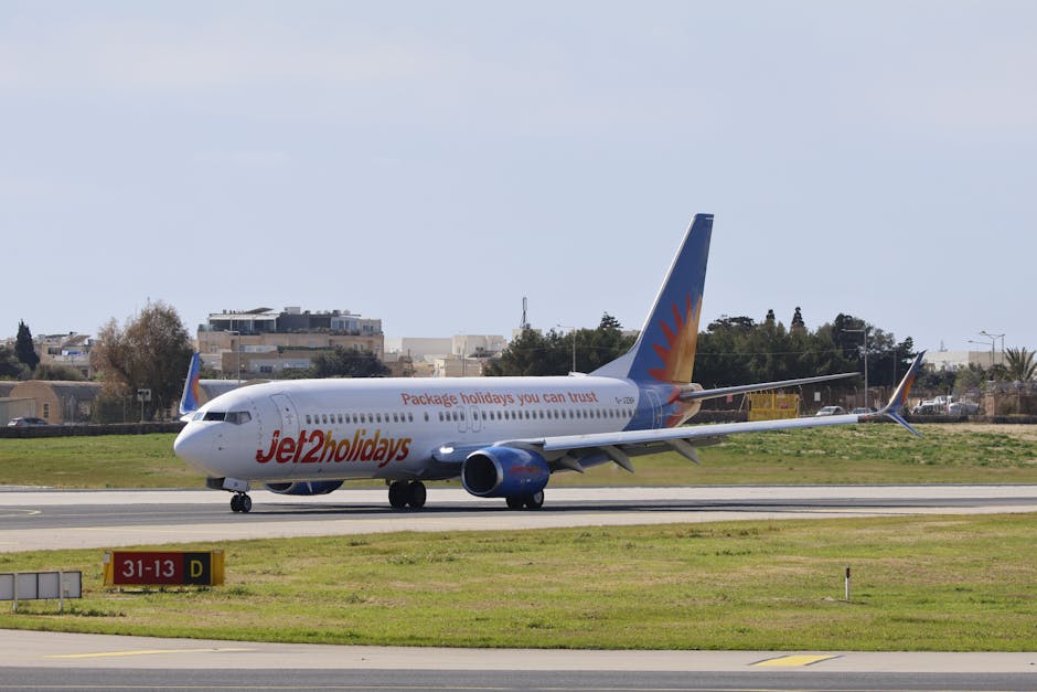 Jet2holidays airplane taxiing on a sunlit runway in a city airport setting.