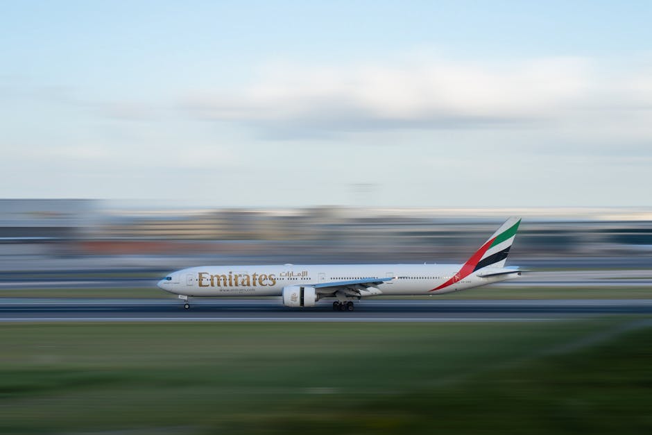 Emirates airplane speeding on runway with motion blur effect, illustrating travel excitement.