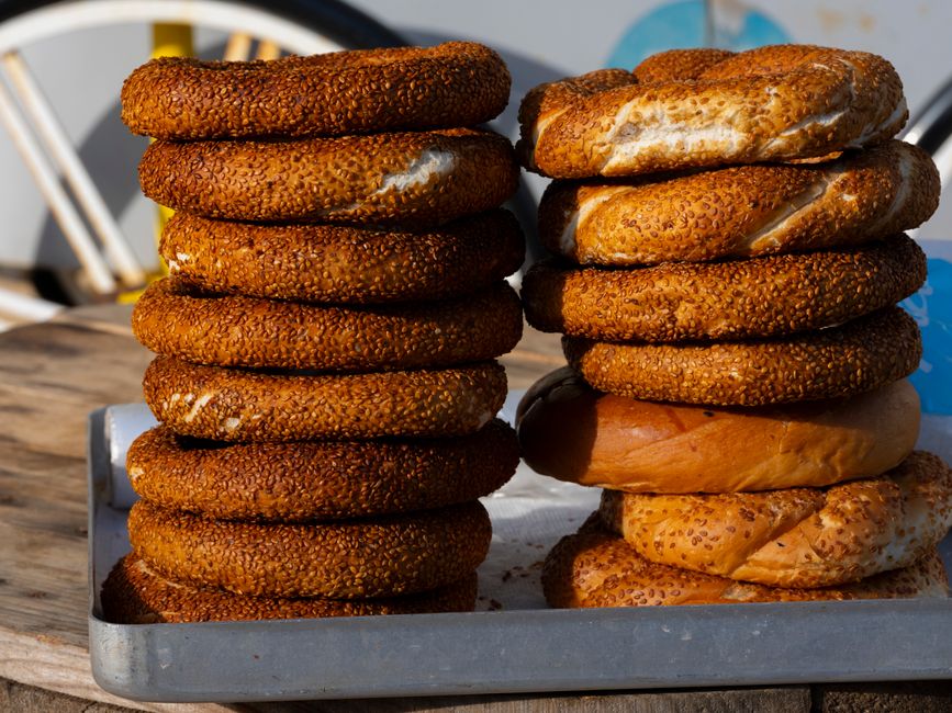 Freshly baked Turkish simit bread stacked on a tray outdoors in Antalya, Türkiye.