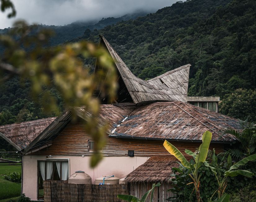 A picturesque view of a traditional Thai house nestled in lush mountains, capturing nature's serene beauty.