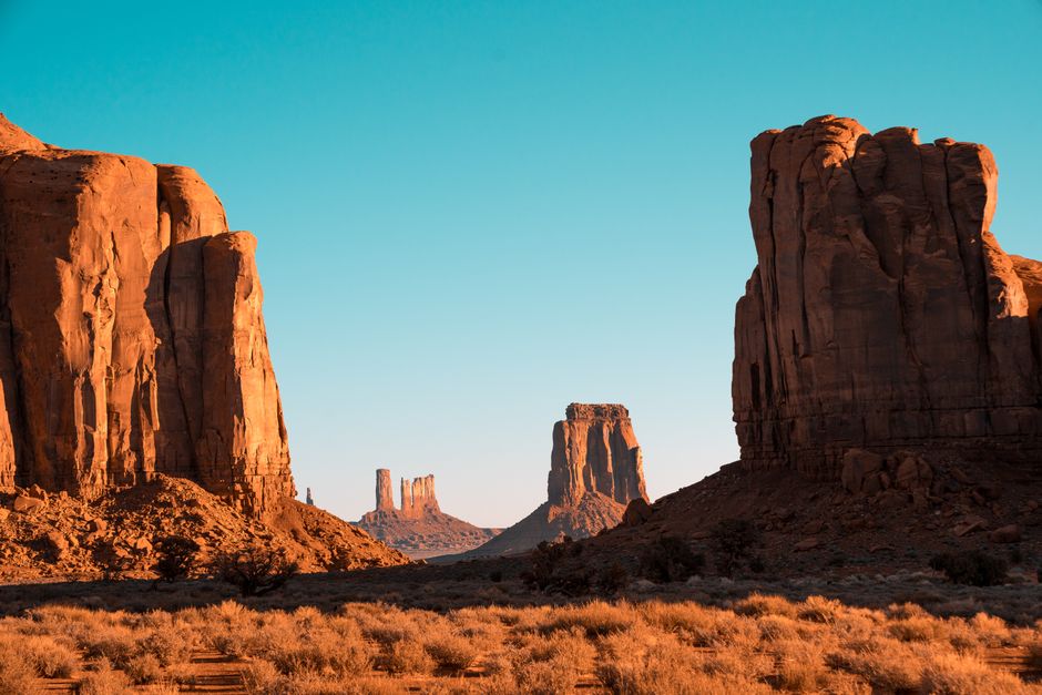Breathtaking sunset view of Monument Valley's iconic buttes in Utah, capturing the vibrant desert landscape.