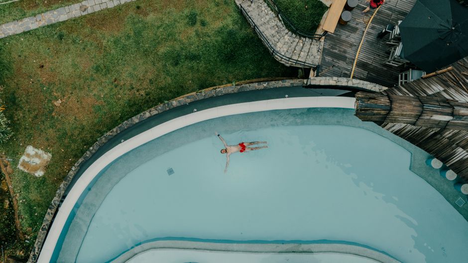Aerial shot of a man floating peacefully in a resort pool surrounded by lush greenery, Sri Lanka.