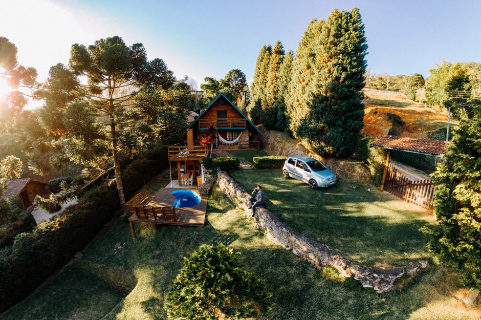 Aerial view of a wooden cabin surrounded by lush greenery in São Bento do Sapucaí, SP, Brazil.