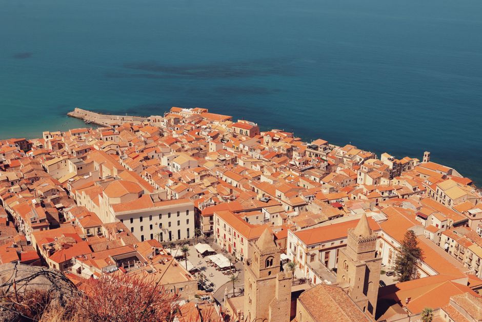 Explore the stunning aerial view of Cefalù, Sicily, showcasing its historic structures and coastline.