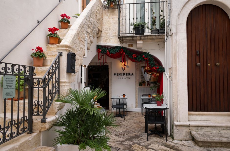 Picturesque Italian courtyard with festive decor and Vinifera cafe, perfect for romantic strolls.