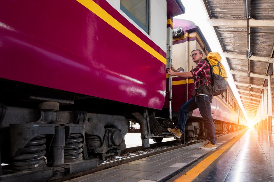 Man with backpack boarding a train at urban railway station during daytime travel adventur