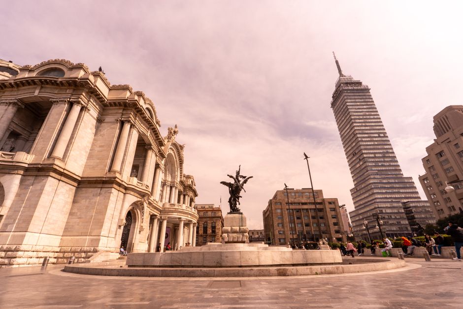 Wide view of Mexico City's Palacio de Bellas Artes and Torre Latinoamericana with vibrant sky.