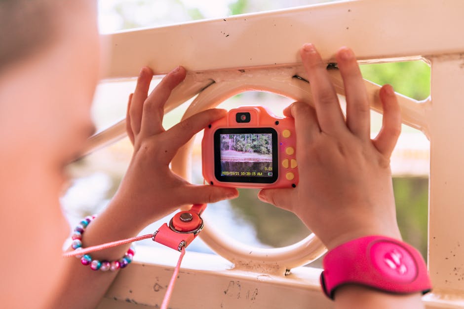 A child uses a pink toy camera outdoors, capturing the scenery, embodying creativity and exploration.