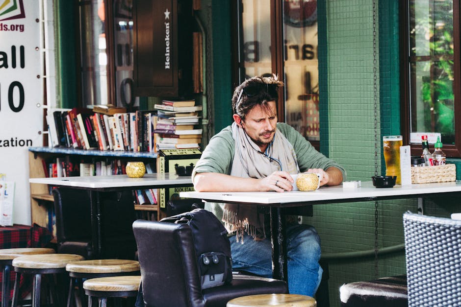 A man enjoys a leisurely moment at a café in Hong Kong, surrounded by books and a drink.