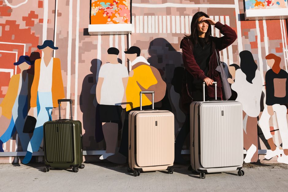 Young woman with suitcases in front of a vibrant urban mural