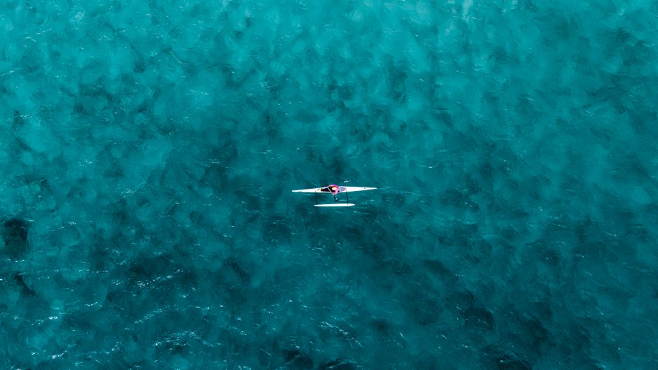 Drone shot of a single kayaker paddling in the stunning blue waters of Hawaii.
