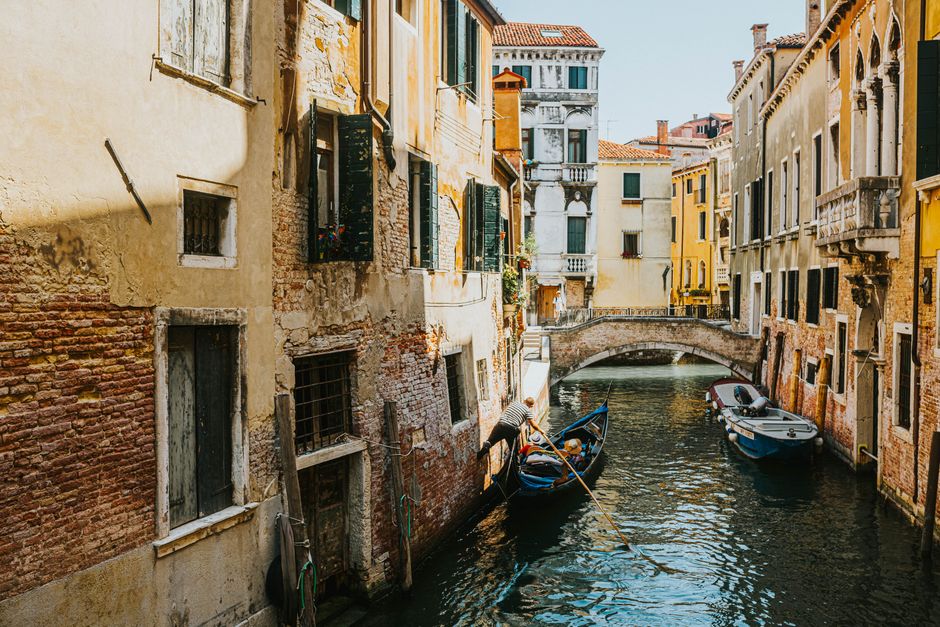 Picturesque view of a Venetian canal with gondolas and historic architecture under a clear blue sky.