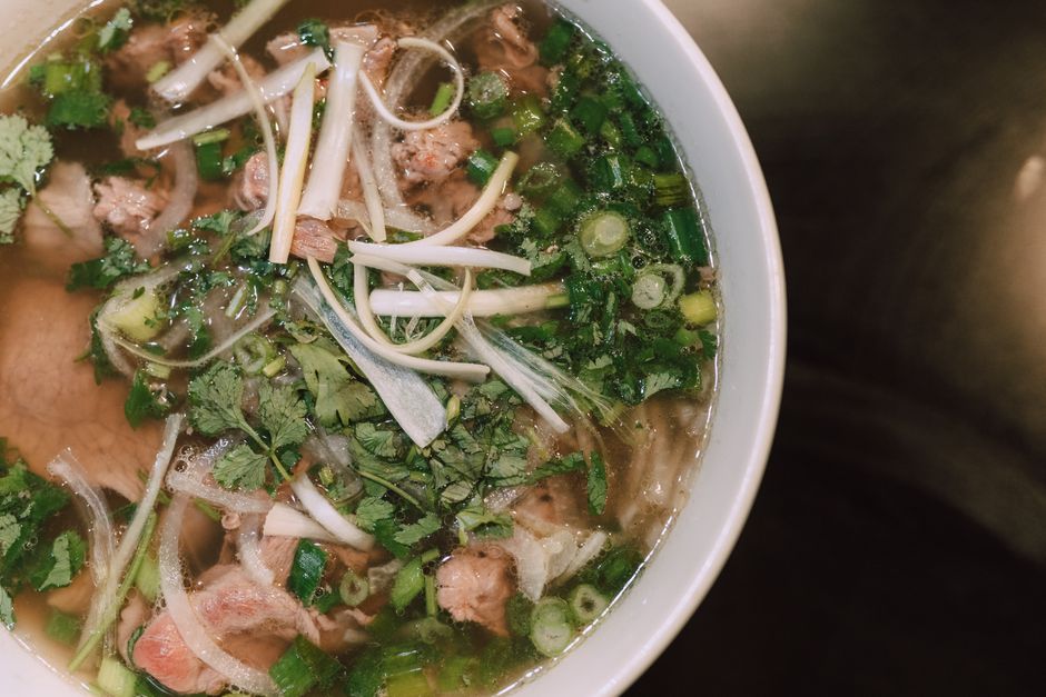 Delicious Vietnamese Pho noodle soup with fresh herbs and beef, captured from above.