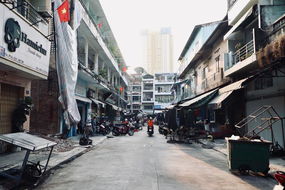 A vibrant street scene in a Vietnamese city with motorbikes and flags.